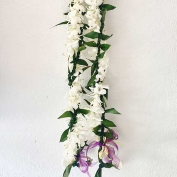 White flower garland with green leaves and a purple ribbon