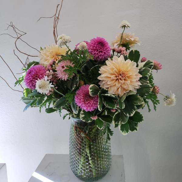 Mixed pink and cream flowers arranged in a glass vase