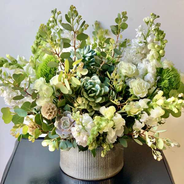 White floral arrangement with succulents in a ribbed container