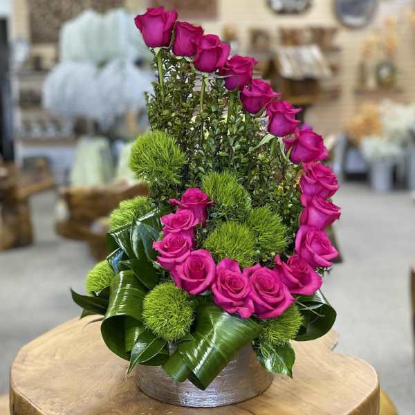 Pink roses arranged with green pom-pom accents in a low round container