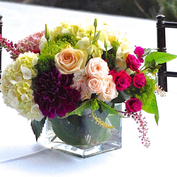 Mixed bouquet of roses, hydrangeas, and dahlias in a clear glass vase