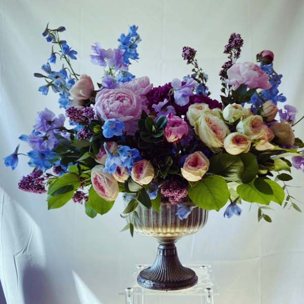 Large bouquet of pink, purple, and blue flowers in a pedestal vase