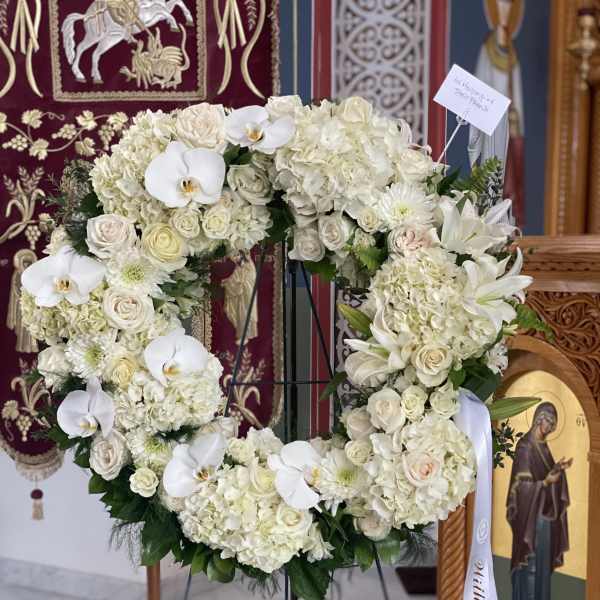 White floral heart wreath on a stand with orchids and roses