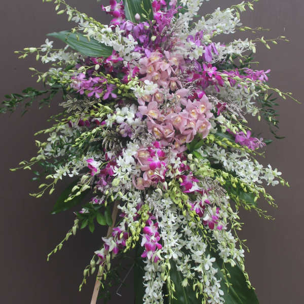 Tall standing arrangement of pink, white, and purple orchids