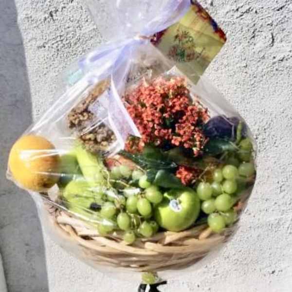Fruit basket with grapes, apples, and flowers wrapped in clear plastic