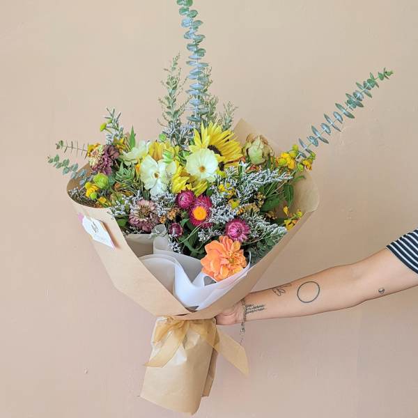 Hand-tied bouquet with sunflowers and mixed blooms in kraft paper