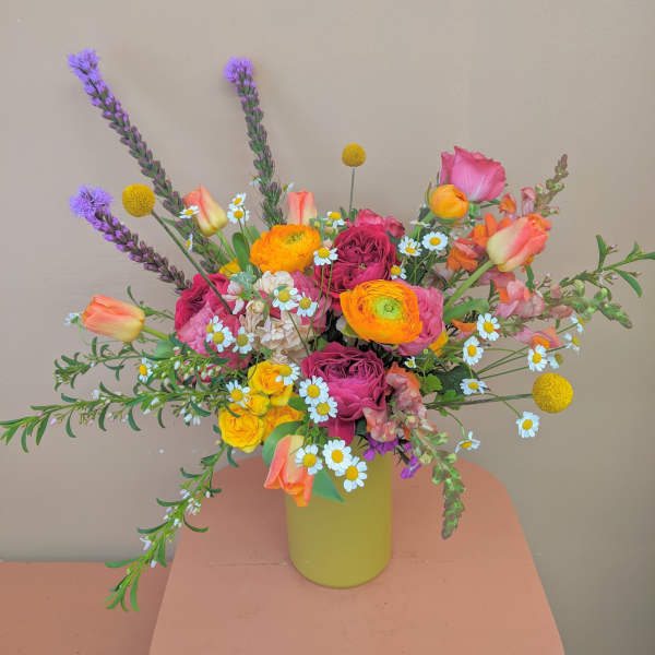 Colorful mixed bouquet in a yellow vase with roses, tulips, and daisies