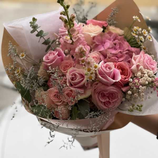 Bouquet of pink roses and small white daisies wrapped in paper