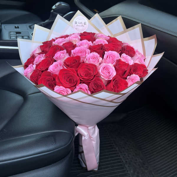 Large bouquet of pink and red roses wrapped in white paper