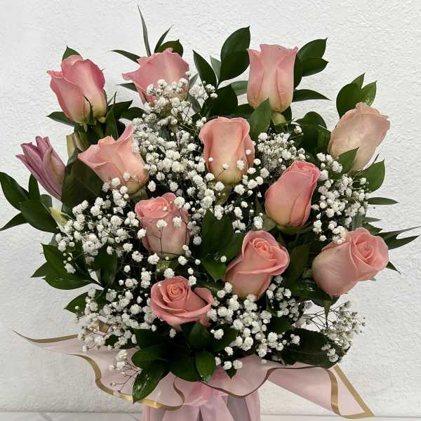 Pink roses and white baby's breath arranged in a pink box with ribbon.