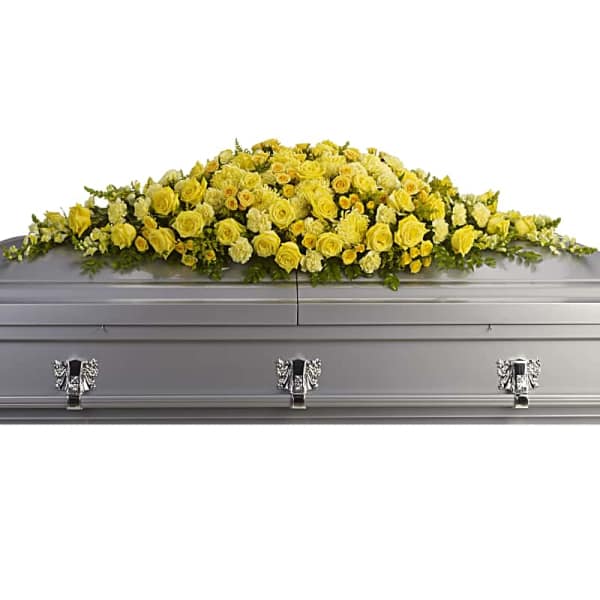 Yellow floral casket spray on a gray casket