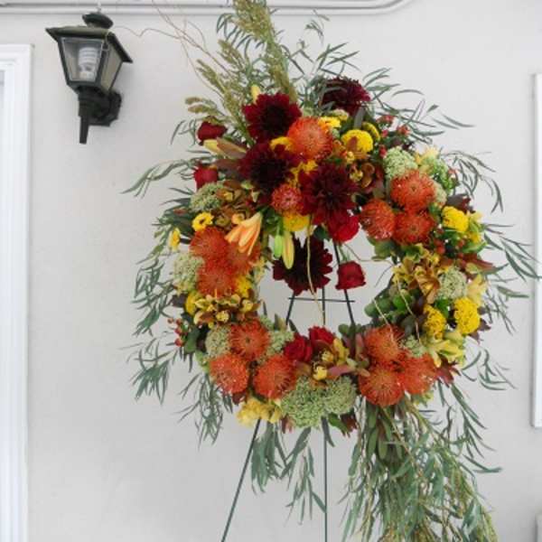 Large floral wreath on a stand with red, orange, and yellow blooms