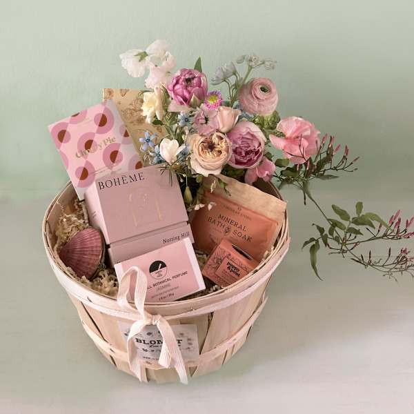Pink flower bouquet in a wooden basket with bath and perfume gifts