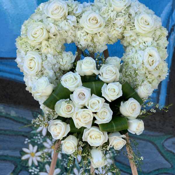 Heart-shaped white rose and hydrangea floral wreath on an easel
