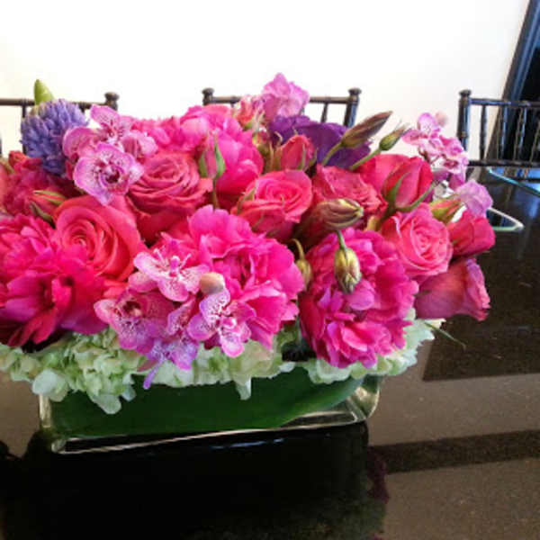Pink and purple floral arrangement in a low rectangular container