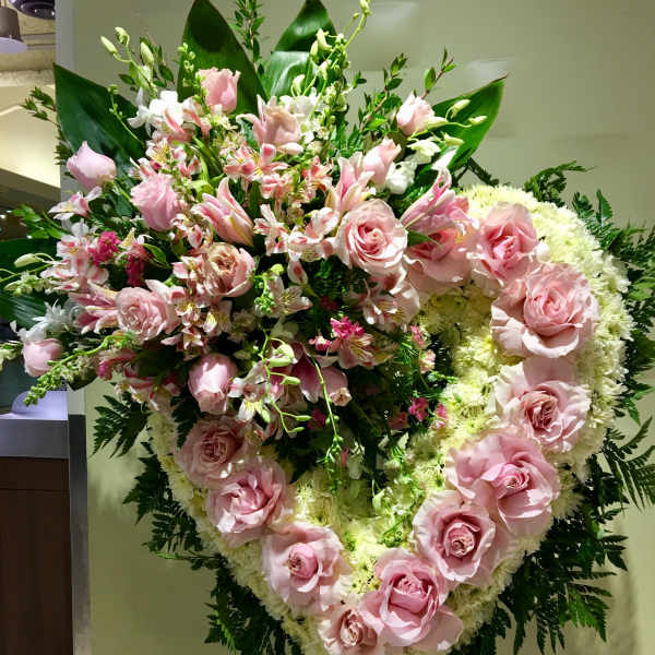 Large pink rose and lily funeral spray on an easel