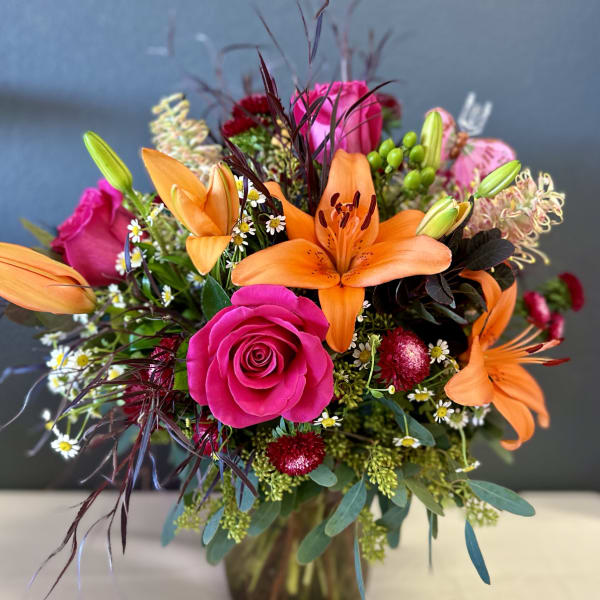 Bright bouquet of orange lilies and pink roses in a glass vase