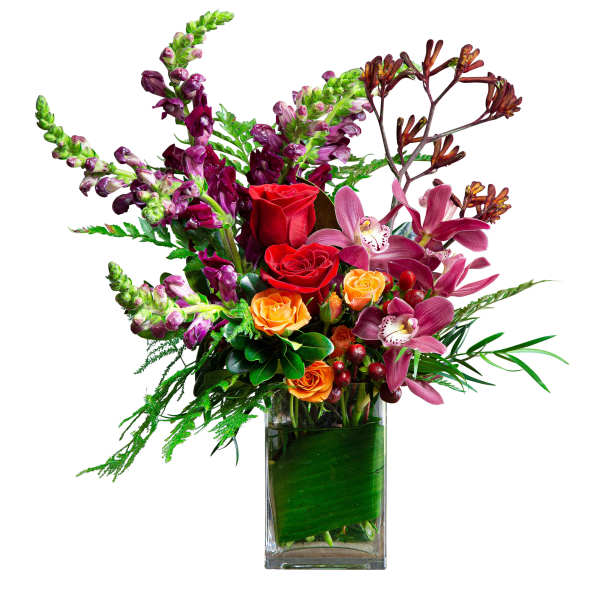 Tall mixed arrangement of red and orange roses, purple snapdragons, and pink orchids in a rectangular glass vase.