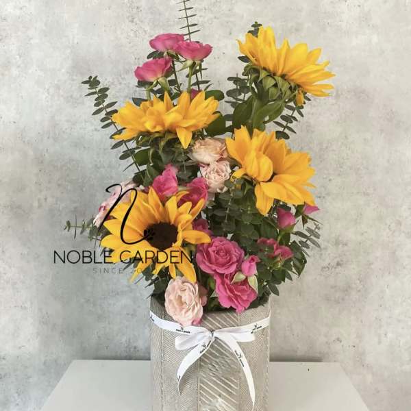 Bouquet of yellow sunflowers and pink roses in a wrapped box