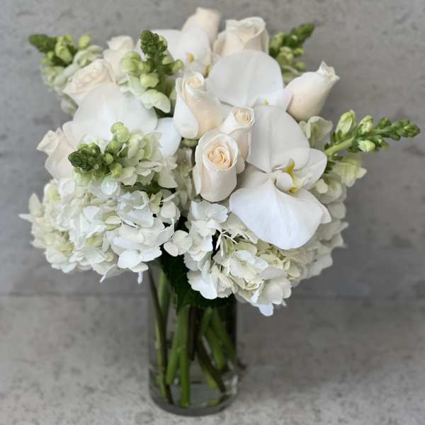 White roses and orchids arranged in a glass vase