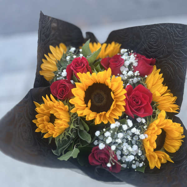 Bouquet of sunflowers and red roses wrapped in black paper