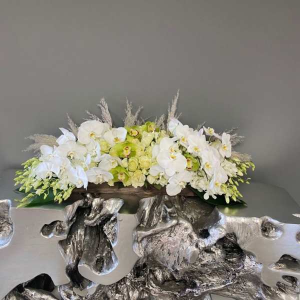 White orchids and pale green flowers arranged in a low centerpiece
