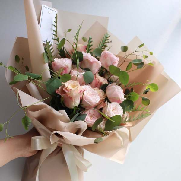 Hand-tied bouquet of pale pink roses with eucalyptus in beige wrap