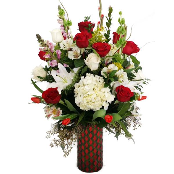 Tall bouquet of red and white flowers in a patterned vase