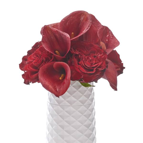 Red calla lilies and roses in a white textured vase