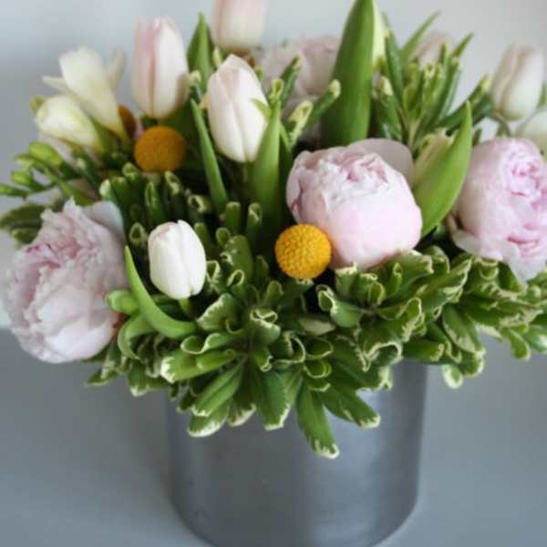 Pink and white tulips with pale peonies in a gray vase