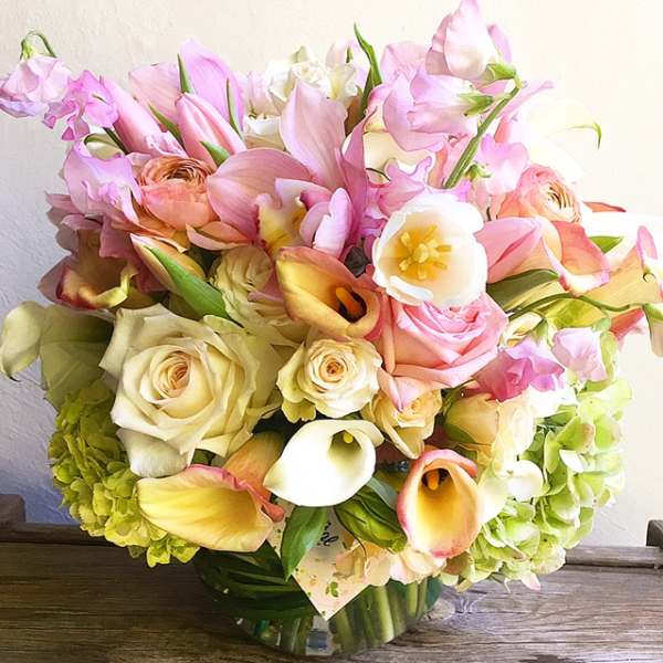 Bouquet of pink tulips, roses, calla lilies, and hydrangeas in a glass vase