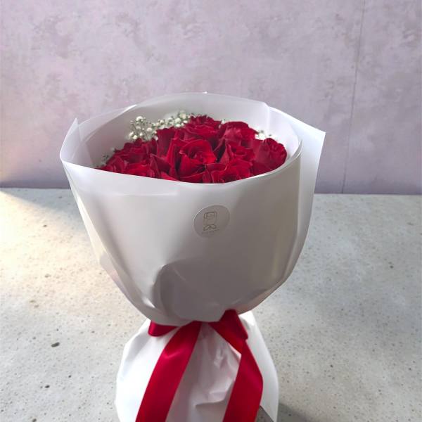 Bouquet of red roses wrapped in white paper with a red ribbon