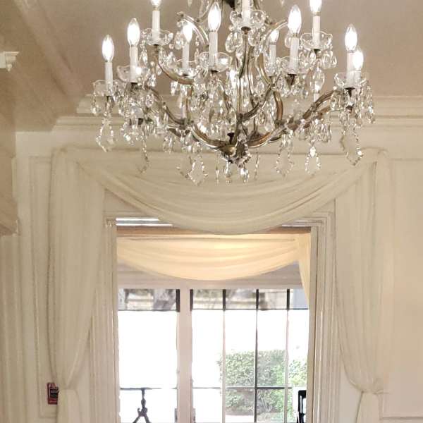 Crystal chandelier above a draped doorway in a bright event space