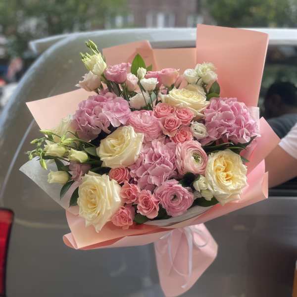 Pink and cream bouquet of roses and hydrangeas wrapped in blush paper