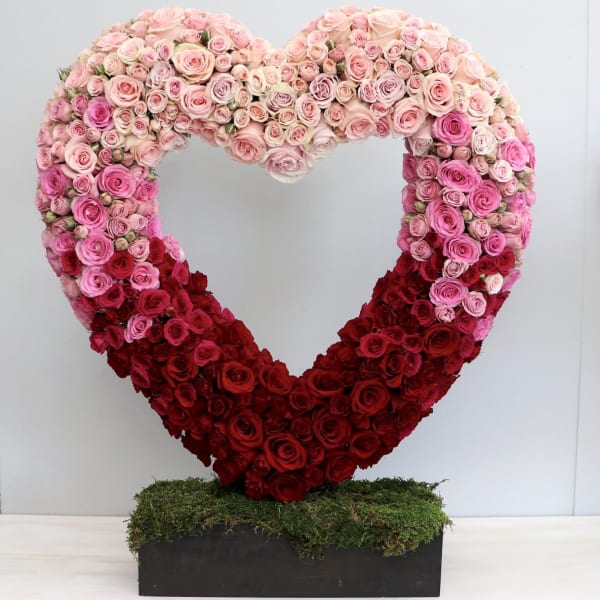 Heart-shaped rose arrangement in pink and red on a rectangular base