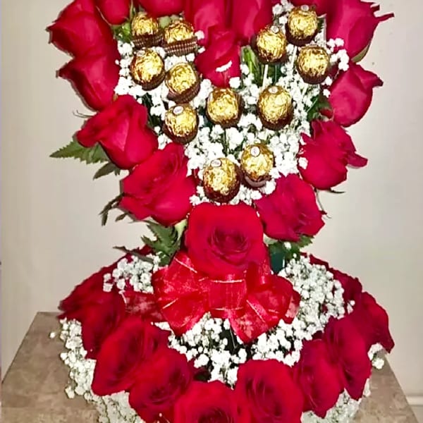 Heart-shaped rose arrangement with gold-wrapped chocolates and baby's breath