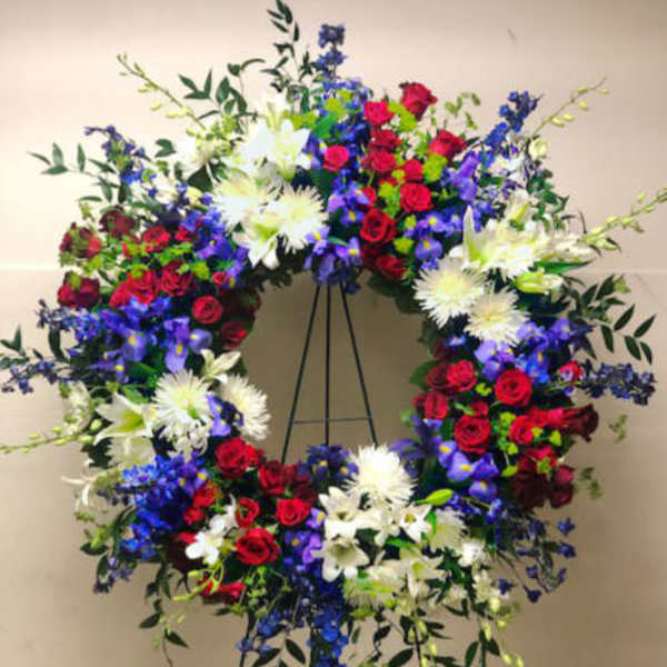Large circular floral wreath on a stand with red, white, and blue flowers