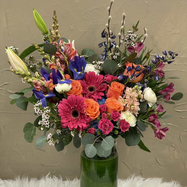 Colorful mixed bouquet in a tall green glass vase