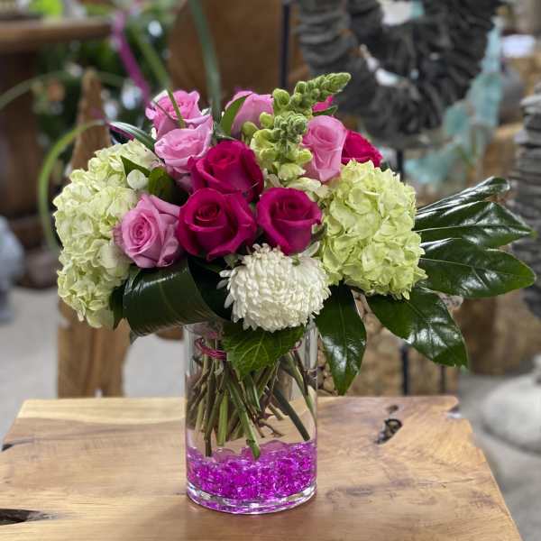 Pink and white roses with pale green hydrangeas in a clear glass vase
