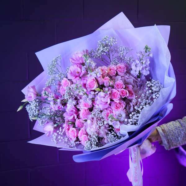 Pink rose and lilac bouquet wrapped in pale paper