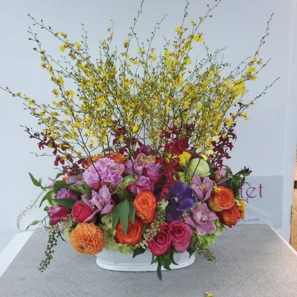 Colorful mixed flower arrangement in a white container