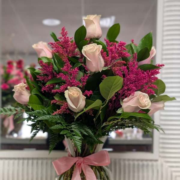 Pink roses and magenta filler in a glass vase with a pink ribbon