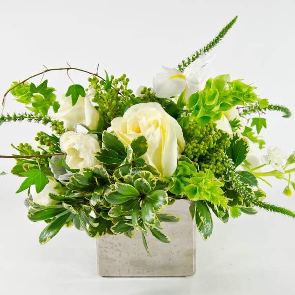 White roses and green flowers in a square glass vase
