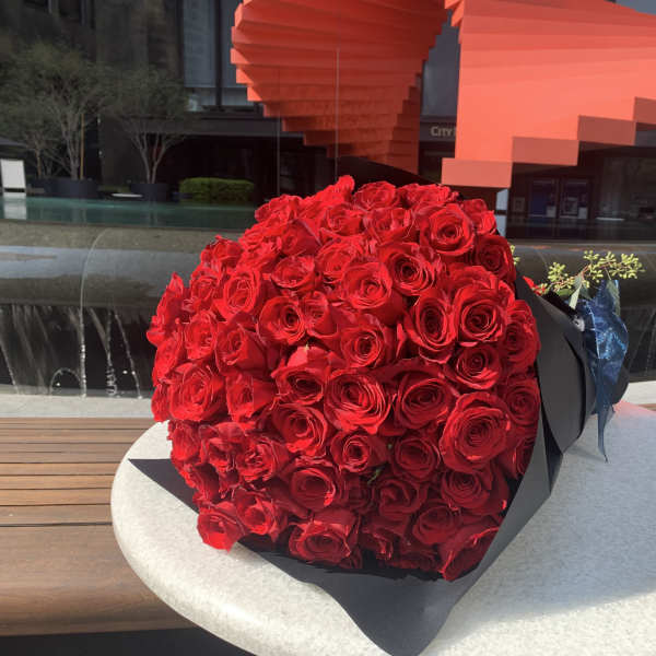 Large bouquet of red roses wrapped in black paper