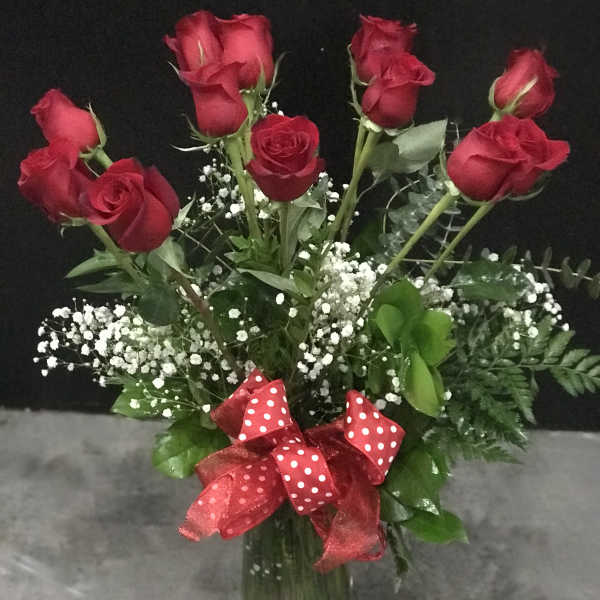 Bouquet of red roses in a glass vase with a red polka-dot ribbon