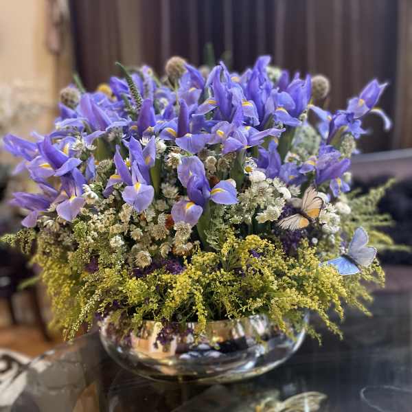 Purple iris arrangement in a low glass bowl with small white filler flowers