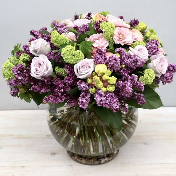 Bouquet of pink and purple flowers in a round glass vase