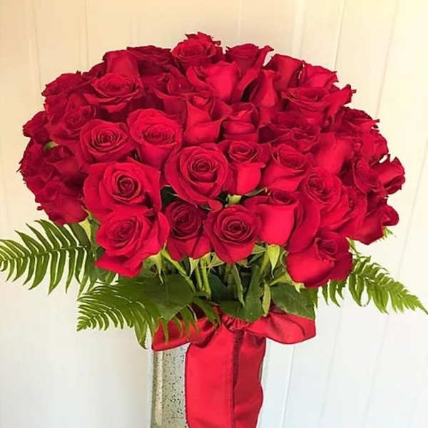 Bouquet of red roses in a tall vase with a red ribbon