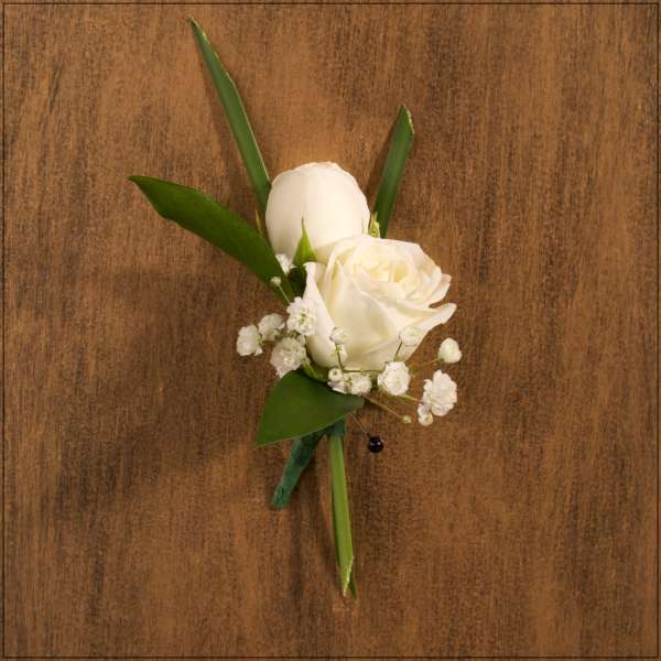 White rose boutonniere with baby's breath and green leaves