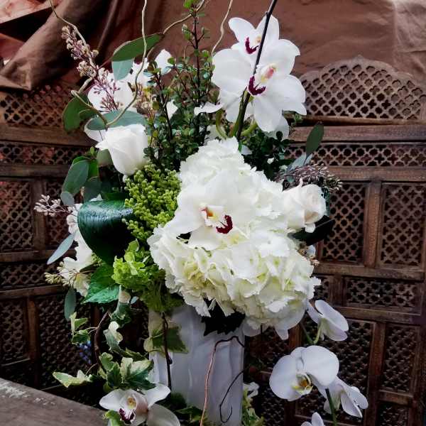 White orchid and hydrangea arrangement in a tall white vase